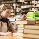 Woman student with headphones studying at wooden library table Woman student with headphones studying at wooden library table - PhotoDune Item for Sale