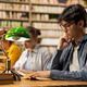 Young asian man with glasses reading book at library study table Young asian man with glasses reading book at library study table - PhotoDune Item for Sale