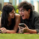 Young woman smiling at partner as they laugh at funny video content Young woman smiling at partner as they laugh at funny video content - PhotoDune Item for Sale