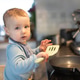 Baby boy standing on learning tower near induction stove with frying pan and holding a spatula in ha Baby boy standing on learning tower near induction stove with frying pan and holding a spatula in ha - PhotoDune Item for Sale