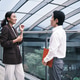 Two young Asian businesspeople cheerfully greet in modern office outdoor. Two young Asian businesspeople cheerfully greet in modern office outdoor. - PhotoDune Item for Sale