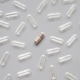 One filled medicine capsule surrounded by empty clear pills on gray background. One filled medicine capsule surrounded by empty clear pills on gray background. - PhotoDune Item for Sale