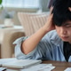 Stressed Asian man holding head in hands while calculating taxes at home Stressed Asian man holding head in hands while calculating taxes at home - PhotoDune Item for Sale