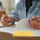 Cropped hands holding tax form with sticky note on desk for financial planning Cropped hands holding tax form with sticky note on desk for financial planning - PhotoDune Item for Sale