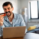 Smiling man working on an e-commerce business at home using laptop and credit card Smiling man working on an e-commerce business at home using laptop and credit card - PhotoDune Item for Sale