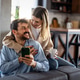 Happy couple enjoying morning coffee at home while browsing their smartphone, showing love Happy couple enjoying morning coffee at home while browsing their smartphone, showing love - PhotoDune Item for Sale