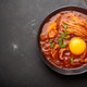 Traditional Korean kimchi jjigae hot soup or stew with egg yolk in black rustic bowl on dark Traditional Korean kimchi jjigae hot soup or stew with egg yolk in black rustic bowl on dark - PhotoDune Item for Sale