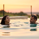 Happy couple swimming in the pool at summer sunset. Happy couple swimming in the pool at summer sunset. - PhotoDune Item for Sale
