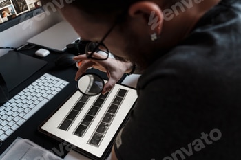 Photographer examining negatives with magnifying glass 2 E116H2T.jpg?w=350&h=350&cf fit=scale down&mark=https%3A%2F%2Fassets.market storefront.envato static.com%2Fwatermarks%2Fphoto 260724