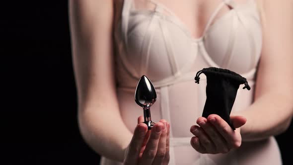 Metal anal plug in the hands of a sexy girl dressed in a white bodysuit. Black background. Takes the, Stock Footage Metal anal plug in the hands of a sexy girl dressed in a white bodysuit. Black background. Takes the, Stock Footage